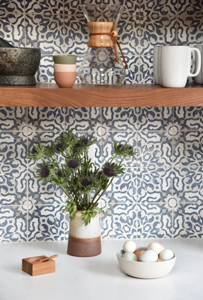 Kitchen remodel: Blue and white patterned tile backsplash under a walnut shelf with quartz counter