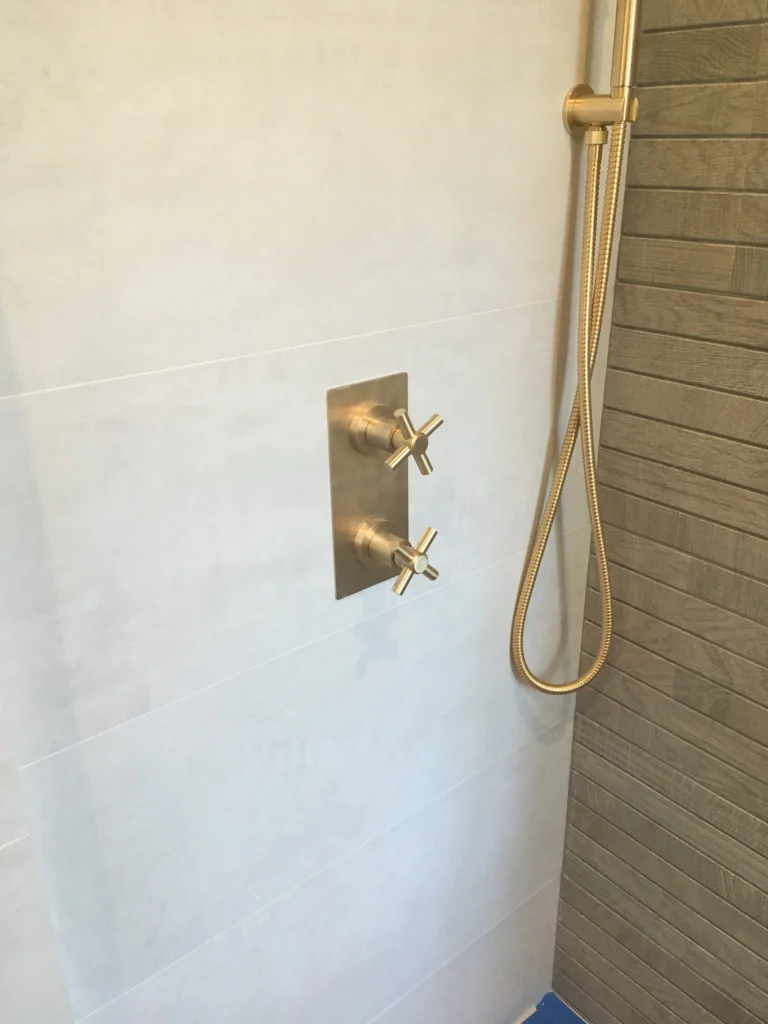 Bathroom remodel: Brushed brass shower valve and hand shower against large white tile, Mill Valley