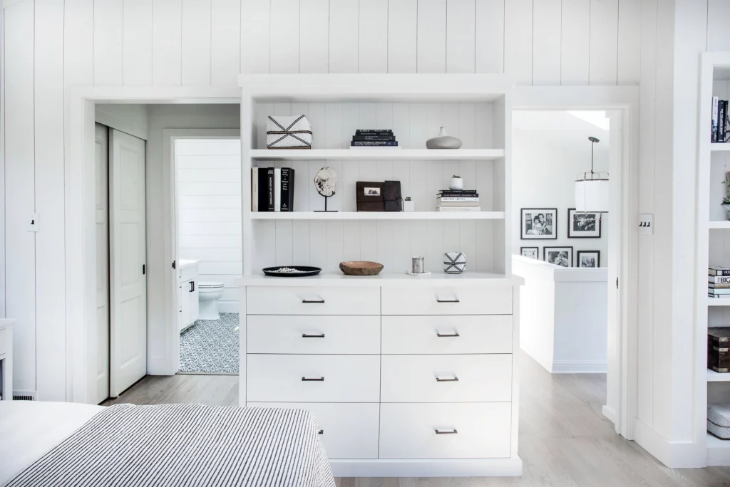 Whole-house remodel: Built-in white dresser and shelves between doorways in a shiplap-panelled bedroom