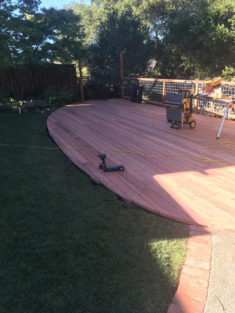 Deck: Curved redwood deck on the lawn, nearly finished, Peacock Gap, San Rafael