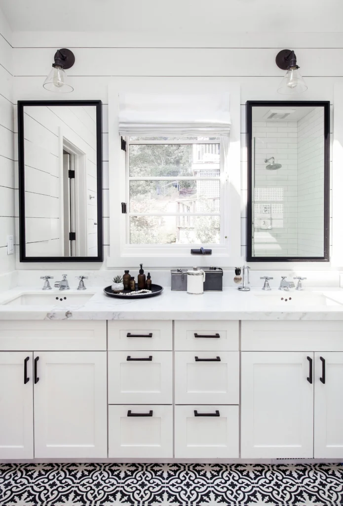 Bathroom remodel: White double vanity with marble top, black-framed mirrors, sconces and patterned floor tile