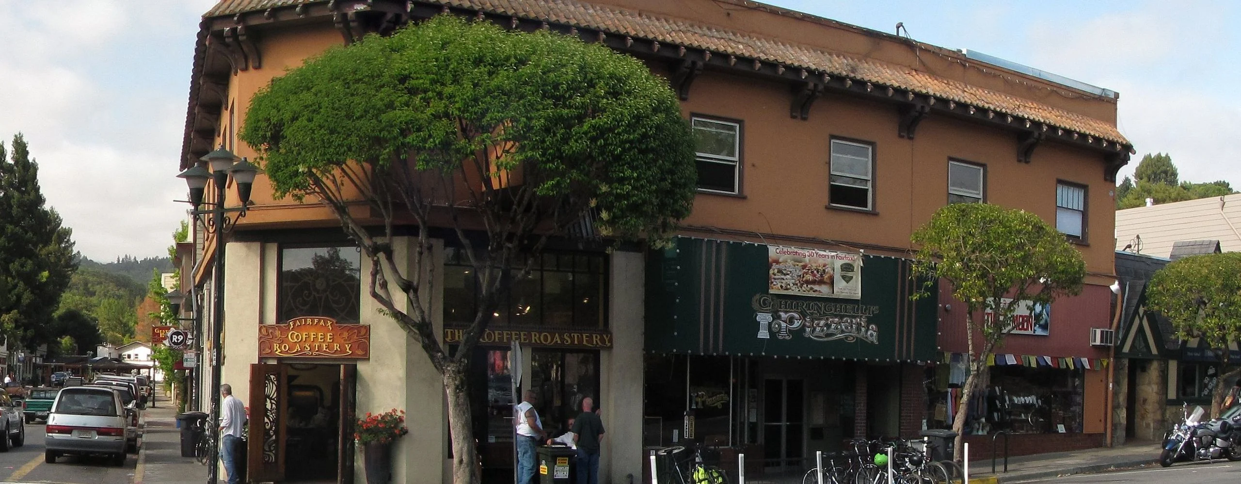 Shops on a street corner in downtown Fairfax, with wooded hills behind
