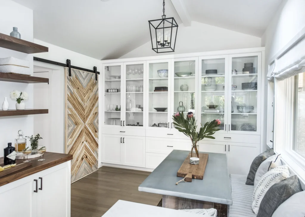 Kitchen remodel: Wall of glass-front built-in cabinets, chevron wood barn door and walnut-topped bar counter