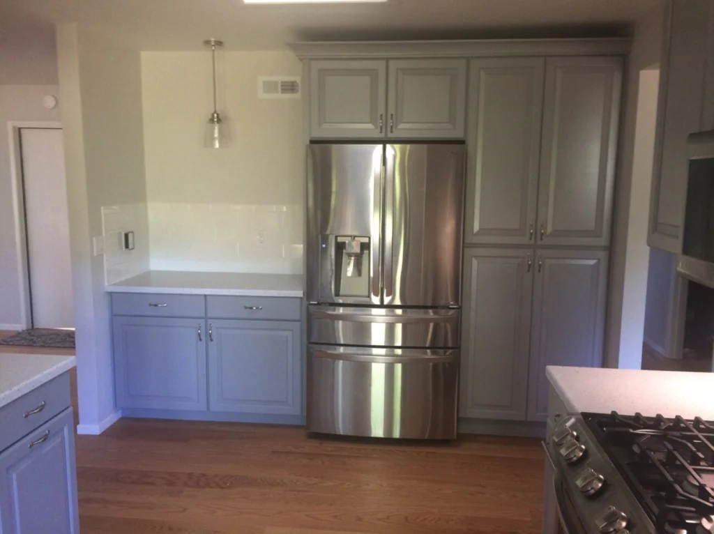 Flooring: Grey raised-panel cabinets around a stainless French-door fridge, white subway tile and glass pendant