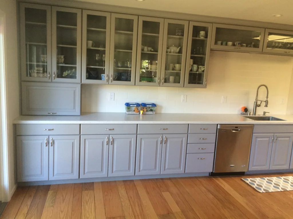 Kitchen remodel: Grey kitchen with glass-front upper cabinets, quartz counters and oak floor, Novato