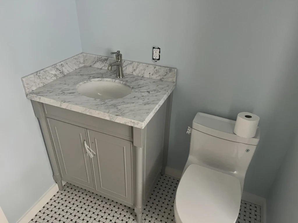 Bathroom remodel: Grey vanity with marble top over black and white hex floor tile