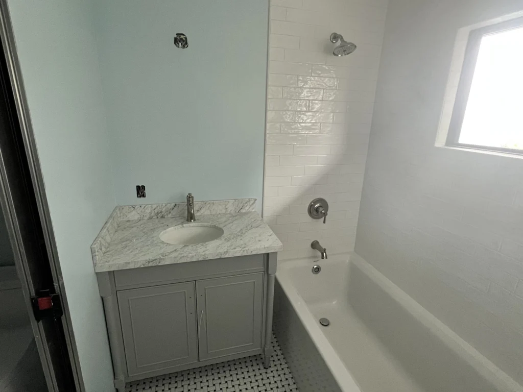 Bathroom remodel: Grey vanity beside a tub with white subway tile surround