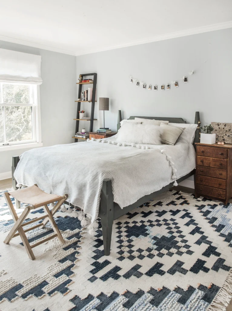 Whole-house remodel: Light grey bedroom with crown moulding, white double-hung window and blue-and-white rug