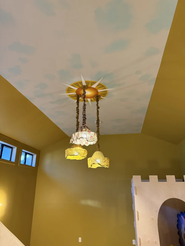 Whole-house remodel: Playroom with a painted cloud ceiling, chandelier and castle wall, Bolinas