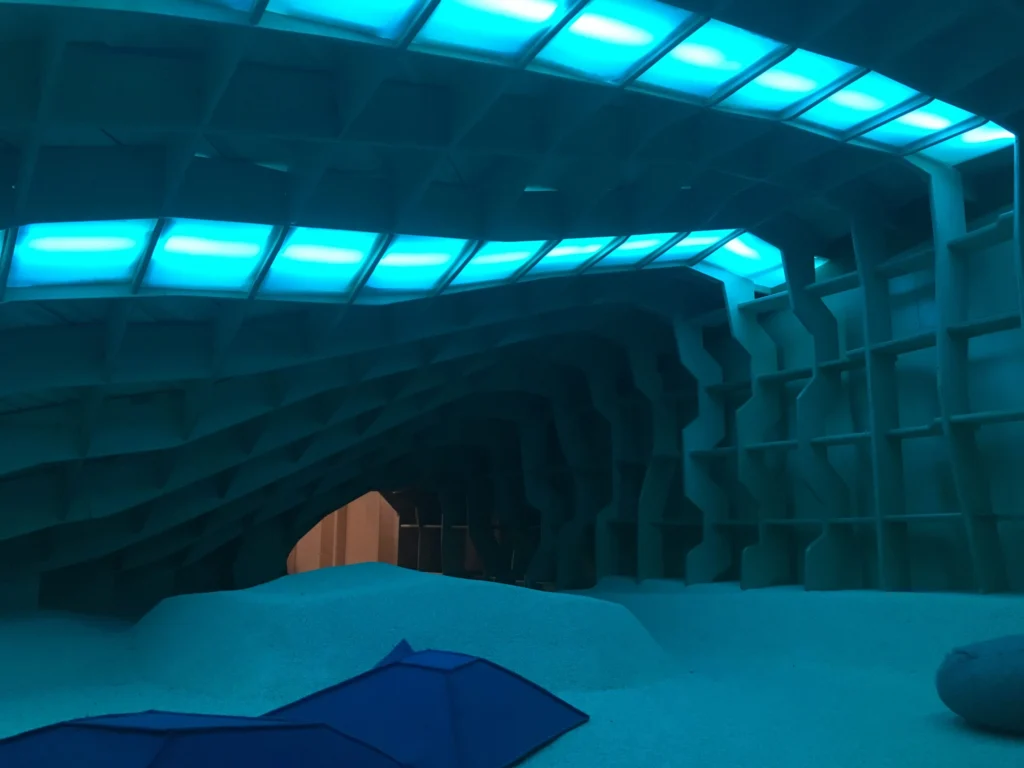 Whole-house remodel: Ribbed play cave with a teal light strip over a soft floor