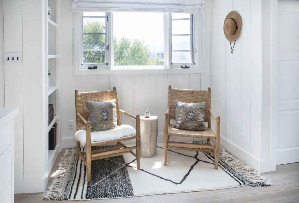 Whole-house remodel: Sitting nook under casement window with vertical board walls and two woven chairs
