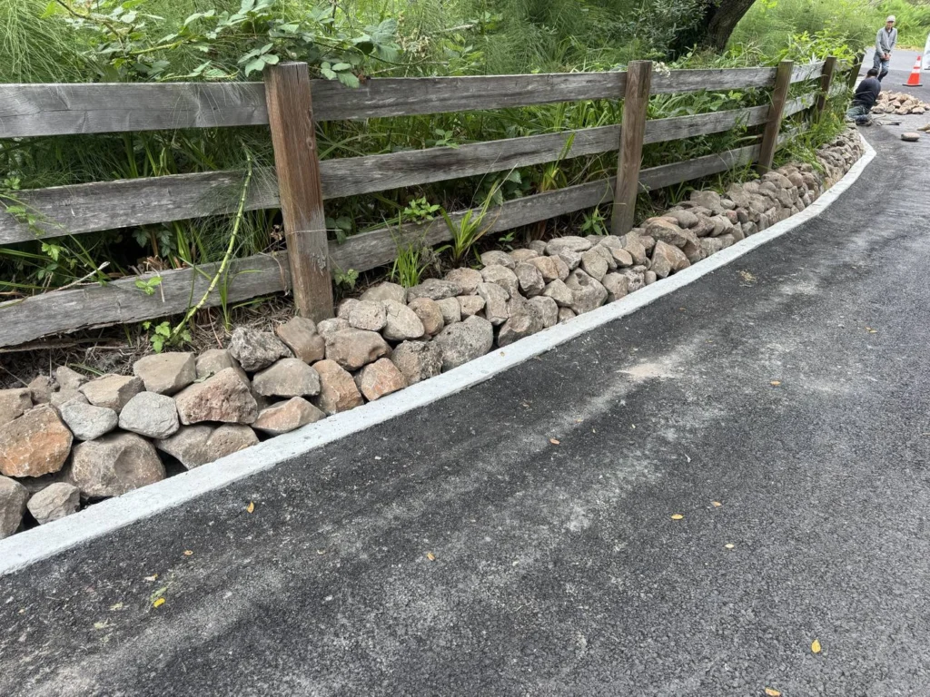 Fencing: Rock edging and rail fence along a newly paved driveway, Bolinas