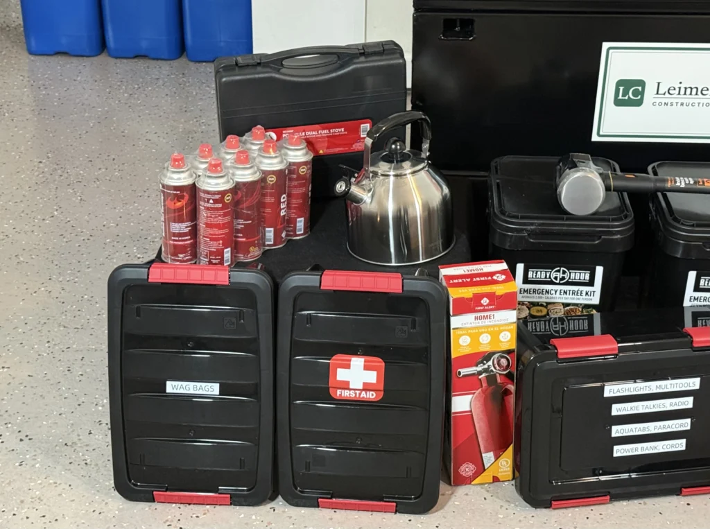 Close up of the cache contents: first aid kit, cooking fuel canisters, a kettle and supply cases