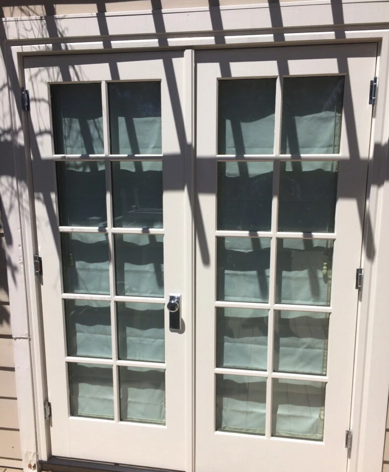 Window replacement: White ten-lite French doors opening onto a deck under a trellis